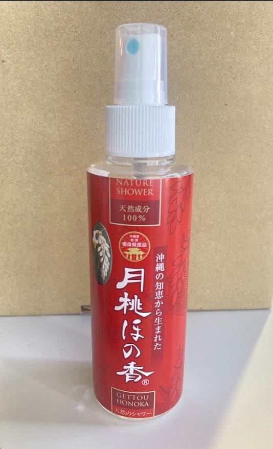 一个红色的喷雾瓶，米色背景上写着“自然淋浴”字样。 白色喷嘴和盖子。